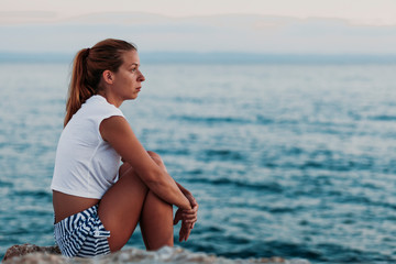 Fototapeta na wymiar Woman sitting on the rock looking to the sea