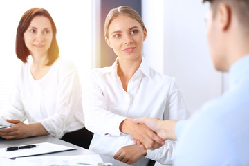 Obraz premium Business handshake by blonde woman and her partner at meeting. Concept of success and agreement