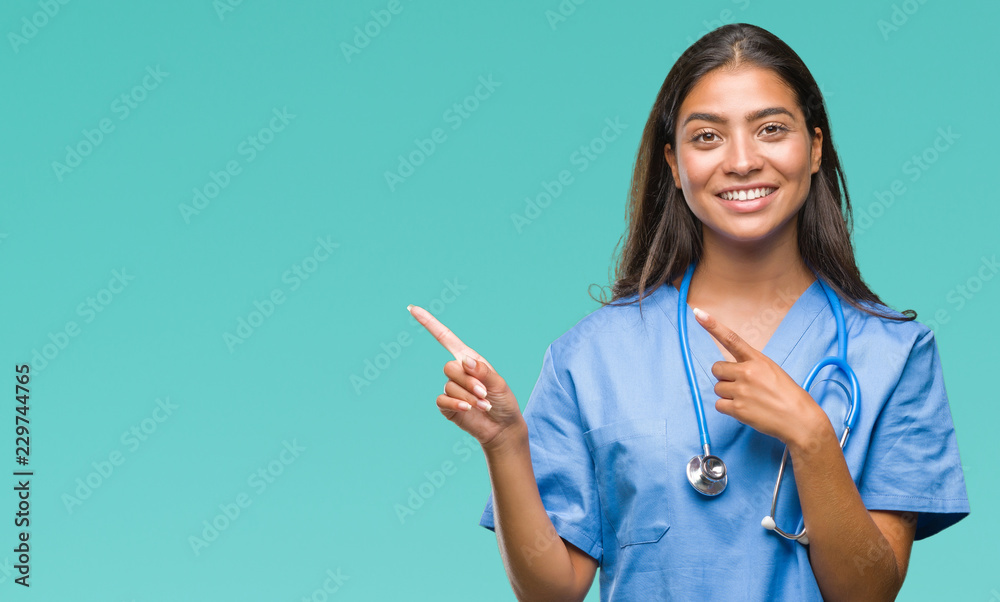 Poster Young arab doctor surgeon woman over isolated background smiling and looking at the camera pointing with two hands and fingers to the side.