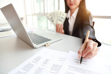 businesswoman signing contract with money on hand