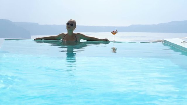 Young woman relaxing in the pool with a gorgeous view on Santorini