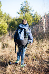 handsome man guy tourist standing alone by the mountain forest landscape during his summer vacation with his backpack back view