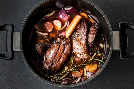 Leg of lamb in red wine with onions, carrots and rosemary in casserole
