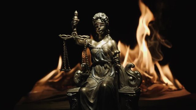 Statue of Lady Justice on the background of the flame of a burning book