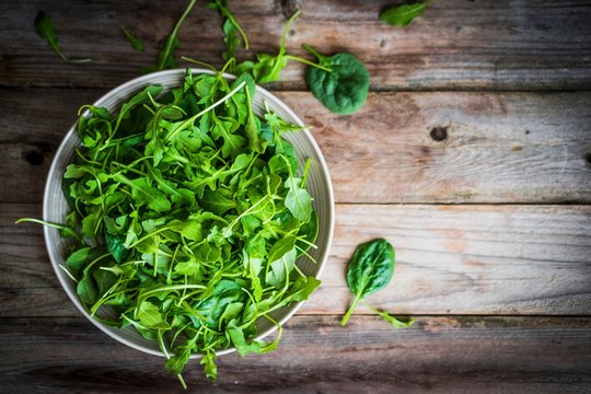 Fresh rocket and spinach salad on a wooden surface