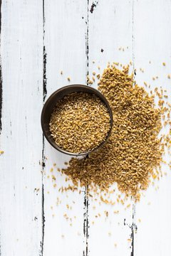 Coarsely crushed freekeh in a bowl and on a wooden surface