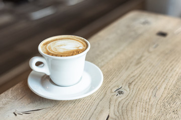 close-up shot of cup of delicious cappuccino on rustic wooden table