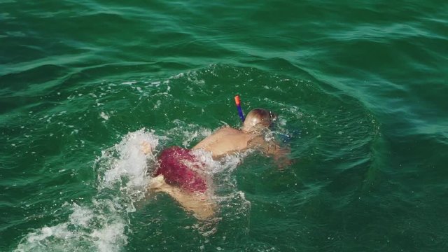 adult man in red shorts is swimming under water in a mask and with snorkel in the sea in the summer. Slow motion