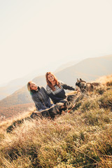 Naklejka na ściany i meble Two girl in the top of mount play with two husky. Ukrainian Carpathians in autumn time. Warm colored green leaves.Forests and mountains view. Travel with dog.