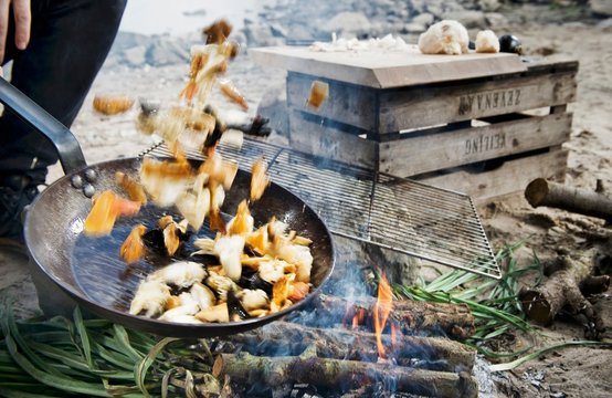 Food tossed in pan over campfire