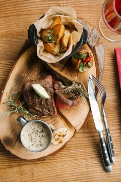 Steak with roasted potatoes and mushroom sauce served on a tree slab