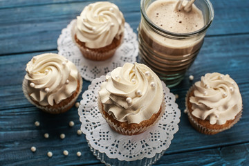 Tasty cupcakes with cup of coffee on wooden table