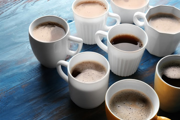 Many cups with tasty aromatic coffee on color wooden table