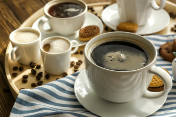 Cups with tasty aromatic coffee and cookies on tray