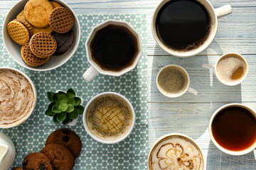 Flat lay composition with cups of tasty aromatic coffee and cookies on wooden background