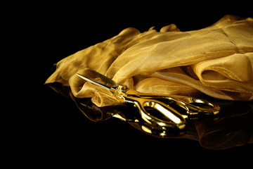 Golden cloth with scissors on black background