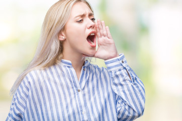 Young blonde woman over isolated background shouting and screaming loud to side with hand on mouth. Communication concept.