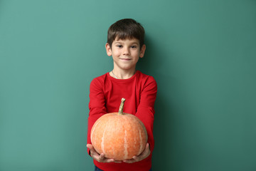 Fototapeta premium Cute little boy with pumpkin on color background