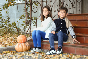 Cute little children with pumpkins sitting on steps outdoors