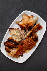 roasted pork on white dish on black background