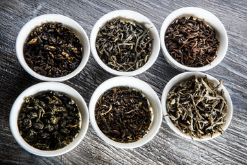 closeup assorted tea leaves in six white small round vessels