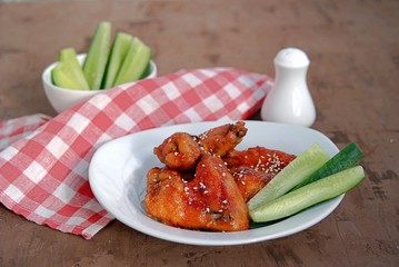 Baked chicken wings in a barbecue sauce, sprinkled with sesame. Served with sliced fresh cucumbers.