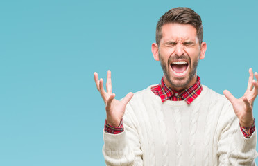 Fototapeta premium Young handsome man wearing winter sweater over isolated background celebrating mad and crazy for success with arms raised and closed eyes screaming excited. Winner concept