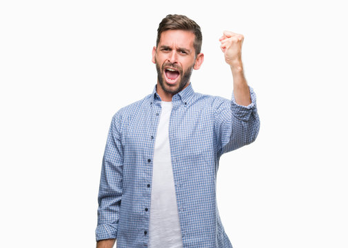 Young handsome man wearing white t-shirt over isolated background angry and mad raising fist frustrated and furious while shouting with anger. Rage and aggressive concept.