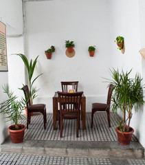 Fototapeta na wymiar Andalusian patio with tables and four chairs wood