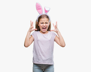 Young beautiful girl wearing easter bunny ears over isolated background crazy and mad shouting and...