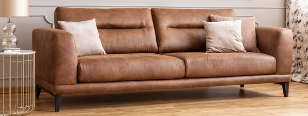 Panoramic view of big comfortable leather sofa with pillows, real photo