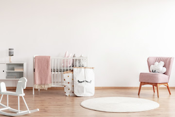 Bright scandinavian baby room with rocking horse, white nursery and pink armchairs, posters on the...