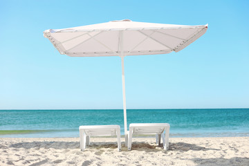umbrella and sun loungers on the beach on a sunny morning with sea background