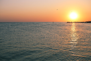 beautiful red sunset on the sea with sun reflection on the water and people standing on the pier