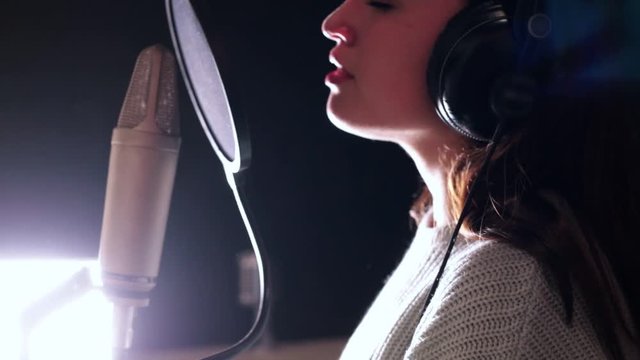 A young attractive woman singing in recording studio