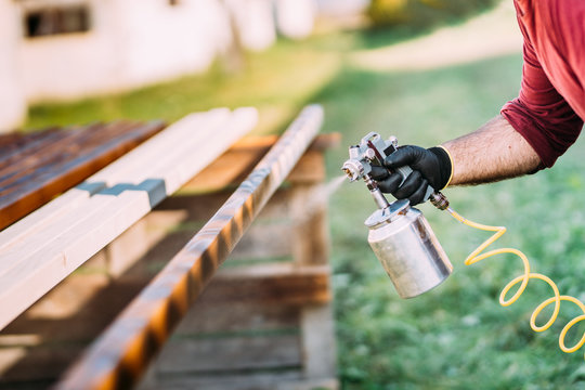 Industrial handyman, male construction worker painting with spray gun on site