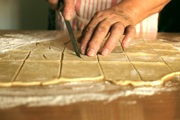 Fototapeta na wymiar hands of an elderly woman cutting the dough into pieces