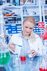 Female laboratory assistant with chemical experiment in scientific laboratory. Female medical or scientific researcher using test tube on laboratory.