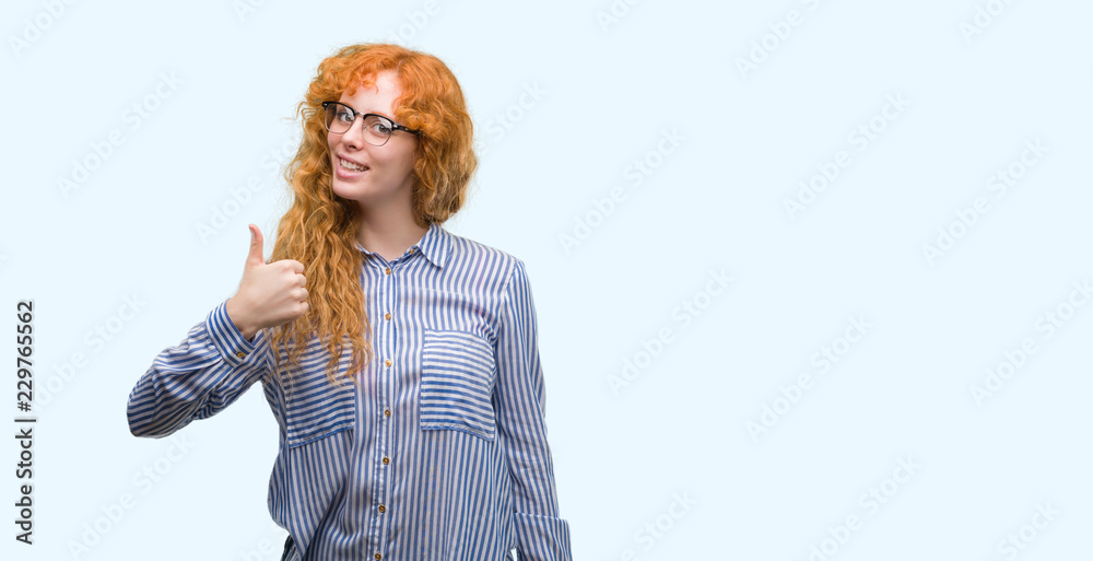 Sticker Young redhead bussines woman doing happy thumbs up gesture with hand. Approving expression looking at the camera with showing success.