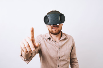 Young man in casual using VR - virtual reality gear and touching something over white background