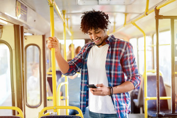 Young modern Afro-American man standing in a public transport and listening to the music.