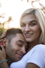 Loving couple standing on grass in nature green park with beautiful sundown light hugging. Man lies on woman's breast.