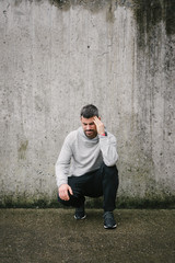 Sick sporty man suffering headache during urban running workout.
