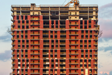 The upper part of the high-rise modern apartment building under construction, the frontal view