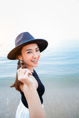 Summer portrait of glamour brown hair young woman wearing black suit, sun hat and happy smile. Standing in the sea