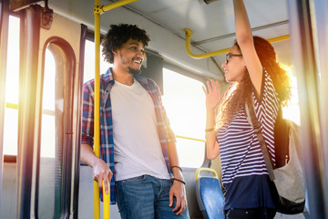 Young cute couple standing in a bus and talking. Mix race couple .