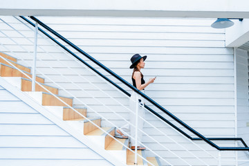 woman in holiday by walk down on stairway with hold mobile