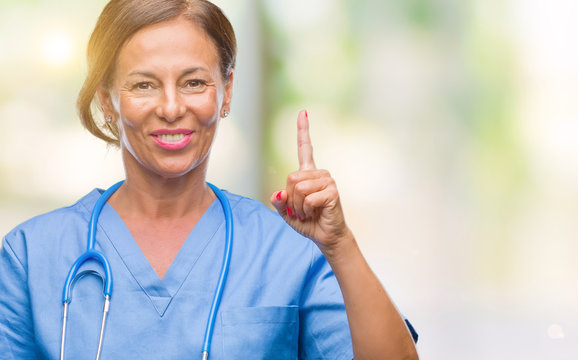 Middle age senior nurse doctor woman over isolated background showing and pointing up with finger number one while smiling confident and happy.
