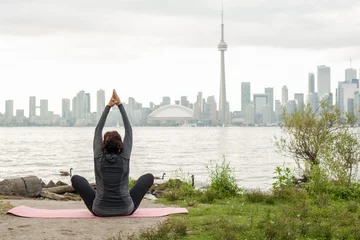 Fotobehang Middle-aged woman practicing yoga at the front of Toronto © rzocky2803