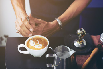 Closeup of barista making latte art focus in milk and coffee in vintage color.selective focus